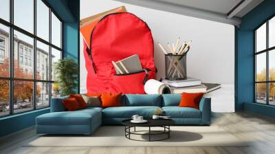 Red school backpack with notebooks, color pencils and scissors on white grunge table near wall Wall mural