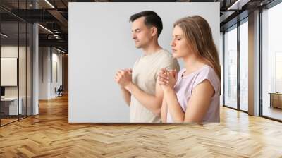 Religious couple praying to God on light background Wall mural