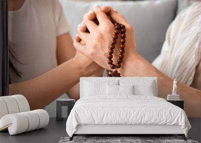 Religious couple praying with beads at home, closeup Wall mural