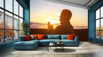 Religious man praying outdoors at sunset Wall mural