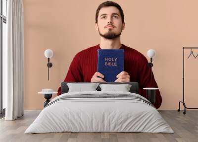 Religious young man with Holy Bible on brown background Wall mural