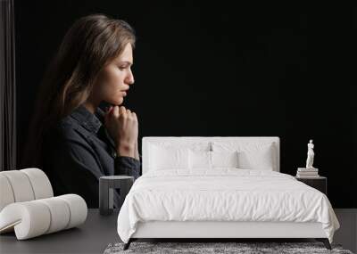 Religious young woman praying to God on dark background Wall mural