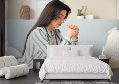 Religious young woman with Holy Bible praying at home Wall mural