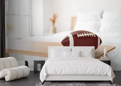 Rugby ball on wooden bench in light bedroom, closeup Wall mural