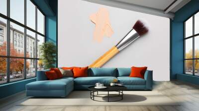 Sample of makeup foundation and brush on light background Wall mural