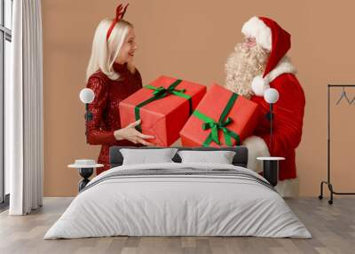 Santa Claus and beautiful mature woman in Christmas deer horns with gift boxes on brown background Wall mural