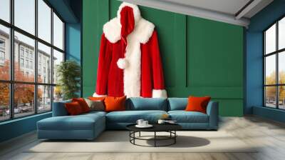 Santa Claus costume hanging on color wall Wall mural