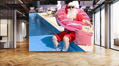 Santa Claus with inflatable ring near swimming pool at resort Wall mural