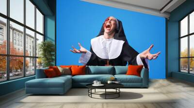 Screaming woman dressed for Halloween as nun on color background Wall mural