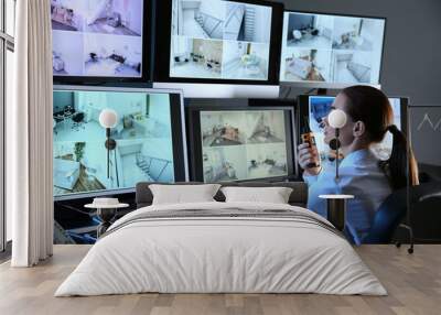 Security guard monitoring modern CCTV cameras in surveillance room Wall mural