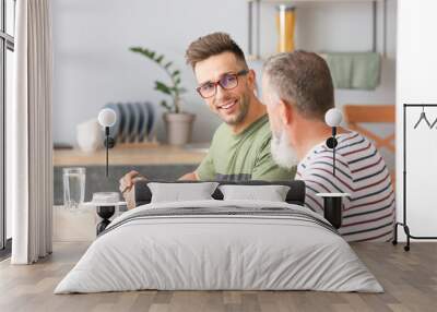 Senior man and his adult son having dinner in kitchen Wall mural