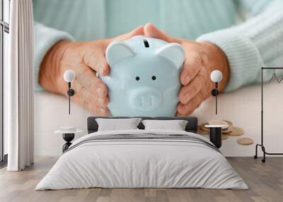 Senior woman with piggy bank at table. Concept of pension Wall mural