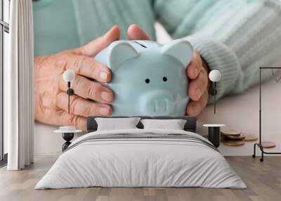 Senior woman with piggy bank sitting at table. Concept of pension Wall mural