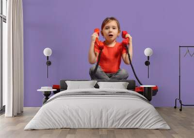 Shocked little girl with retro phones on purple background Wall mural