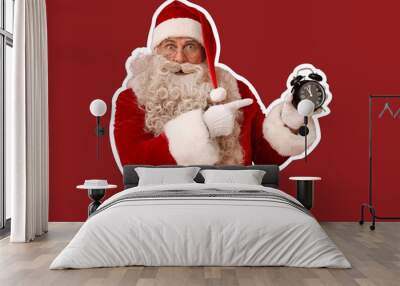 Shocked Santa Claus pointing at alarm clock on red background Wall mural