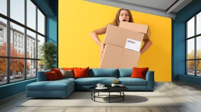 Shocked woman with cardboard boxes on color background Wall mural