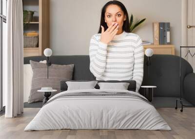 Shocked young woman video chatting at home Wall mural