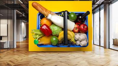 Shopping basket with food on color background Wall mural