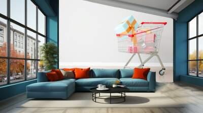 Shopping cart with gifts near light wall Wall mural