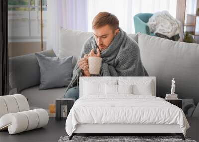 Sick man drinking hot tea at home Wall mural