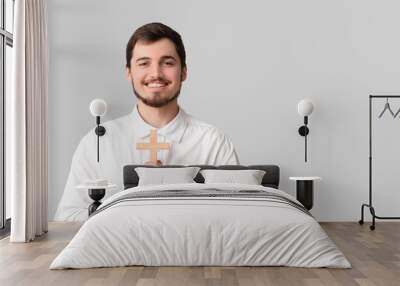 Smiling young man with cross on grey background Wall mural