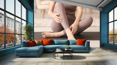 Sporty barefoot woman sitting on fitness mat at home, closeup Wall mural