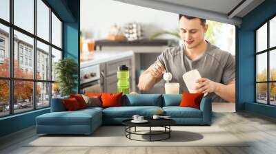 Sporty man making protein shake at home Wall mural