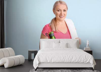 Sporty mature woman with bottle of water on color background Wall mural