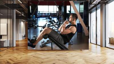 Sporty young man training in gym Wall mural