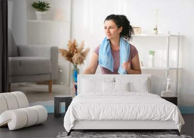 Sporty young woman with bottle of water at home Wall mural