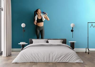 Sporty young woman with bottle of water near color wall Wall mural