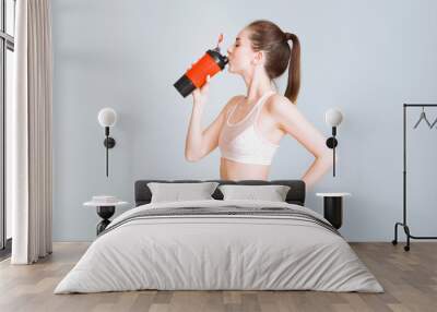 Sporty young woman with protein shake on light background Wall mural