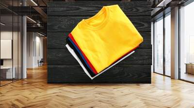 Stack of colorful t-shirts on wooden background Wall mural