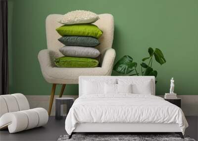 Stack of cushions on armchair and plant near green wall in room Wall mural