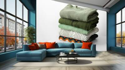 stack of different stylish sweaters on table near light wall Wall mural