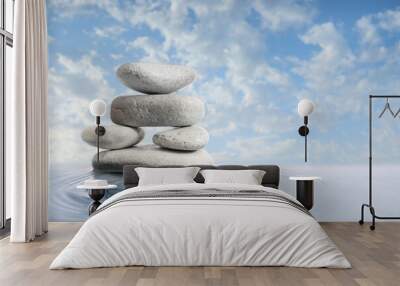 Stack of spa stones in water against cloudy sky Wall mural