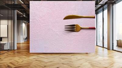 Stainless steel fork and knife on pale pink background Wall mural