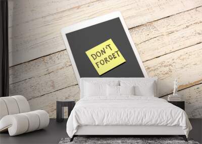 Sticky note with text DON'T FORGET and tablet computer on white wooden background Wall mural