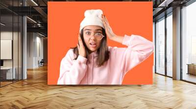 Stressed young woman in eyeglasses on orange background Wall mural