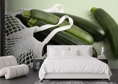 String bag with many fresh zucchini on green wooden background Wall mural