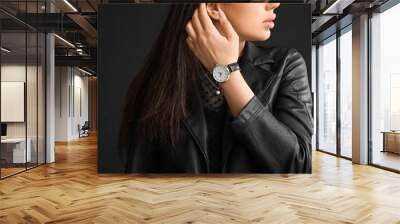 Stylish beautiful woman with wristwatch on black background Wall mural