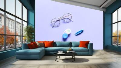 Stylish eyeglasses and contact lenses with container on purple background Wall mural