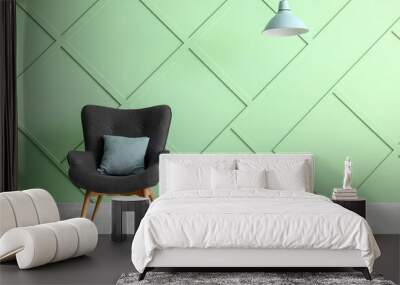 Stylish grey armchair with cushion near green wall Wall mural