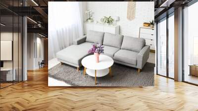 Stylish interior of living room with bouquet of lilacs branches on coffee table near sofa Wall mural