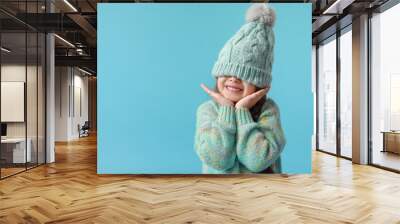 Stylish little girl in winter clothes on color background Wall mural