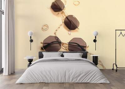 Stylish sunglasses and jewellery on beige background Wall mural