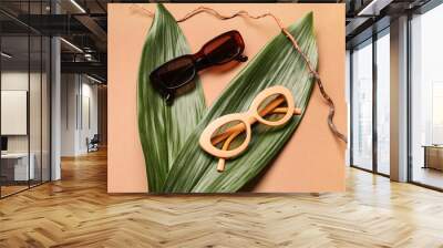 Stylish sunglasses with palm leaves and tree branch on brown background Wall mural