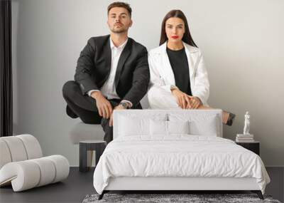 Stylish young couple sitting on bench near white wall Wall mural