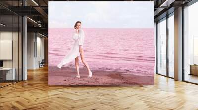 Stylish young woman posing near pink lake on summer day Wall mural