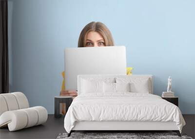 Surprised young woman with laptop on color background Wall mural